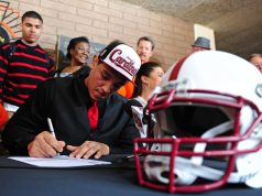 Football Scholarships A group of people sitting at a table with a helmet on