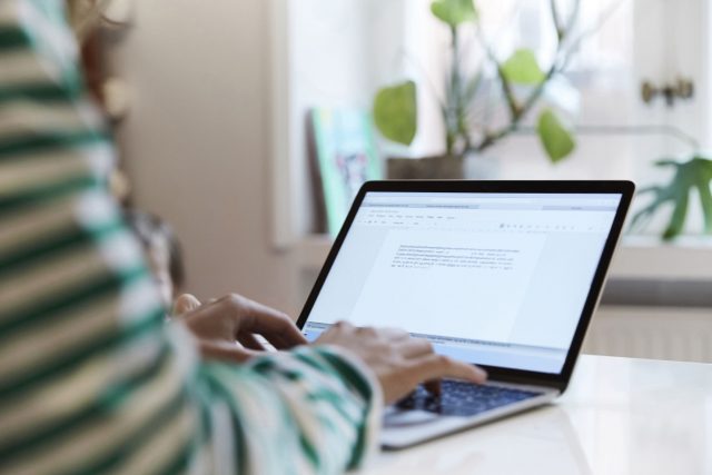 A person using a laptop computer sitting on top of a table