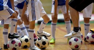 What are the reasons for playing various sports? A group of people standing next to a football ball