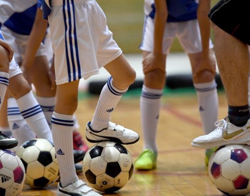 What are the reasons for playing various sports? A group of people standing next to a football ball